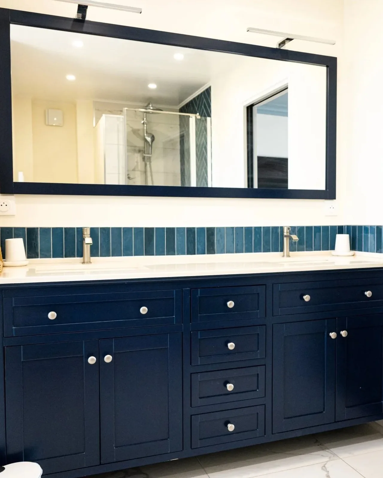 Double vasque bleu marine surmontée d'un grand miroir et d'une crédence en faïence bleue, dans la salle de bain de la Suite La Comtesse.