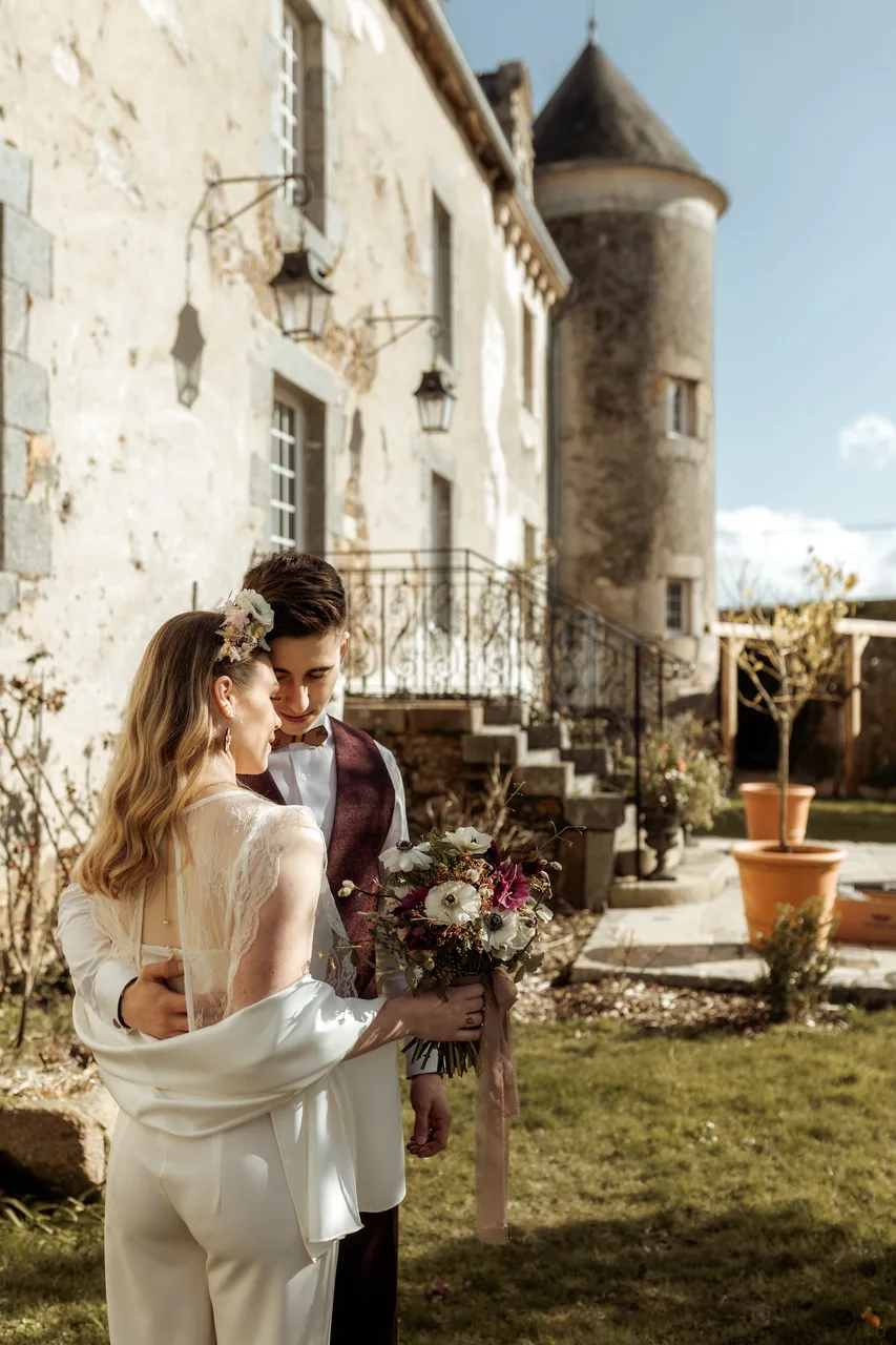 Couple de jeunes mariés enlacés dans les jardins du Manoir La Ville Durand, en tenue de mariage, lors d'un shooting photo romantique